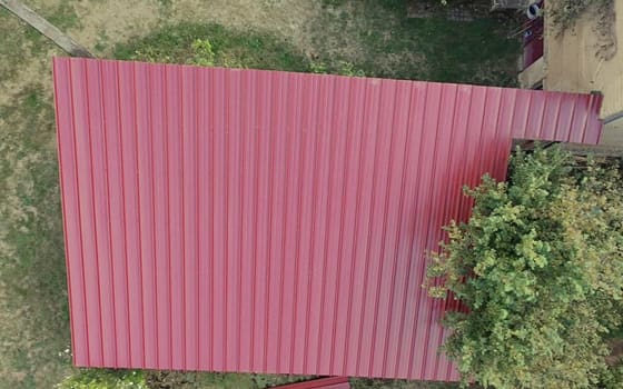 Le même bâtiment couvert en bac acier nervuré rouge, vue du drone.
