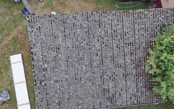 Longue couverture de bâtiment annexe entièrement moussue avant remplacement, vue du drone.