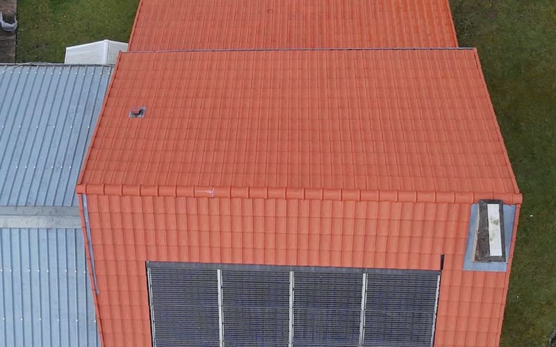 Les deux versants du même bâtiment refaits en tuiles, rives en zinc et panneaux solaires reposés.