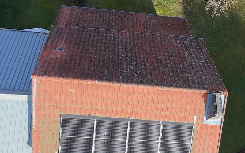 Versant supérieur encore moussu et versant inférieur déjà refait, panneaux solaires en place.