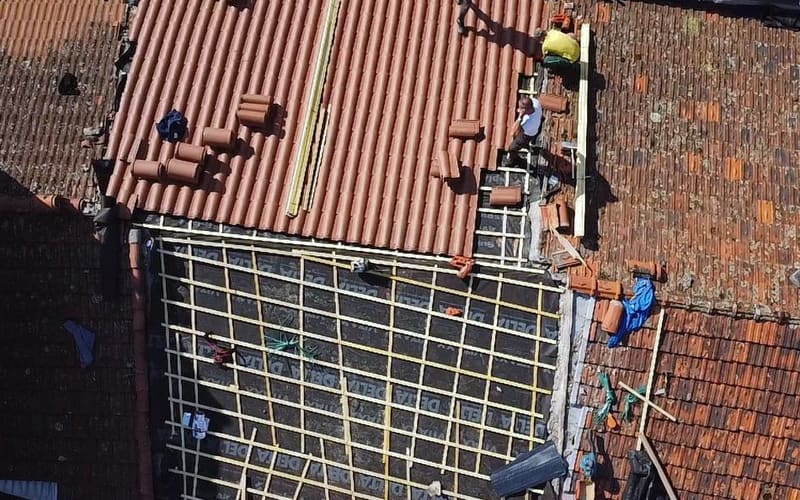 Écran de sous-toiture et contre-lattage posés sur un rampant, tuiles en attente de pose, vue du drone.