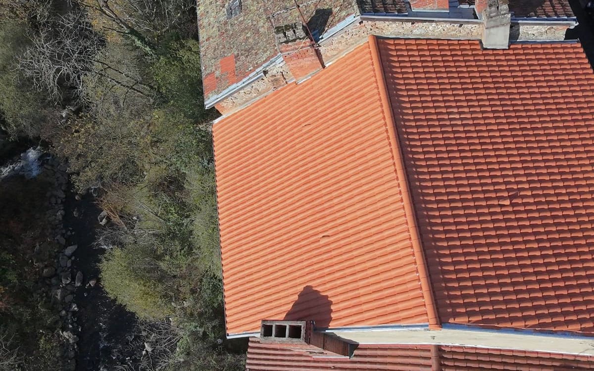 Deux pans de toiture refaits en tuiles au bord d’une rivière, vue du drone.