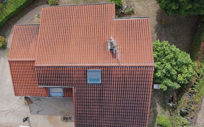 Pavillon en tuiles romanes en cours de démoussage, une partie de la couverture déjà nettoyée.