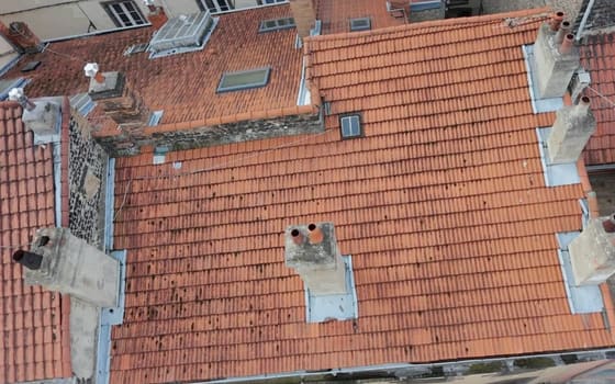 Souches de cheminée, mitrons, solins et noues en zinc sur une toiture de centre-bourg, vue du drone.