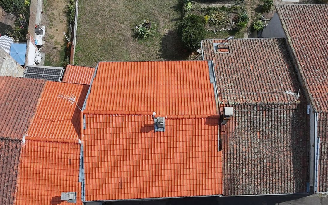 Vue du drone : toiture neuve en tuiles orangées encadrée de deux toitures anciennes envahies de mousses.