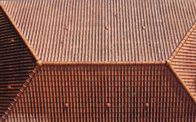 Toiture à quatre pans vue du drone à l’aplomb, tuiles ternies et encrassées avant intervention.