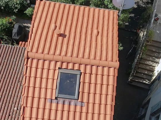 Fenêtre de toit neuve sur un rampant refait en tuiles, solin et bavette plomb.