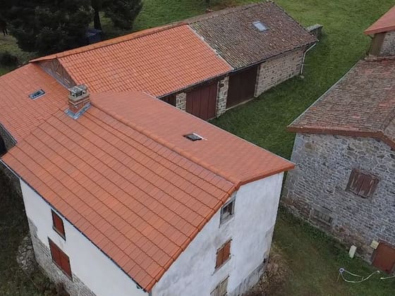 Maison rurale en pierre dont la toiture vient d’être refaite en tuiles.