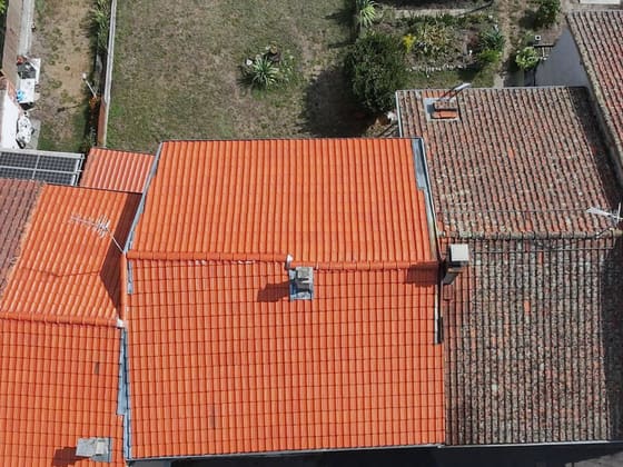 Toiture neuve encadrée de deux couvertures anciennes moussues, vue du drone.