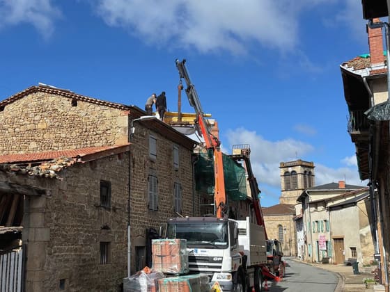 Approvisionnement d’un chantier de couverture en rue de bourg : camion-grue et palettes de tuiles.